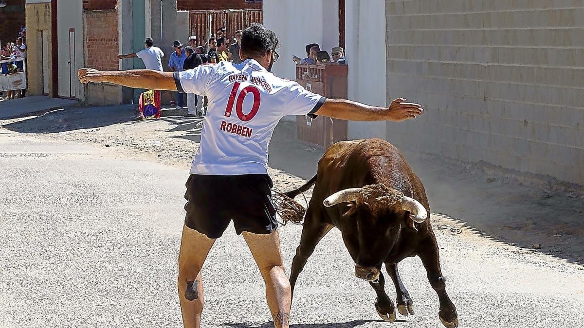 Un joven esquiva a uno de los toros del encierro ante la mirada del público en Pollos.-PABLO REQUEJO / PHOTOGENIC