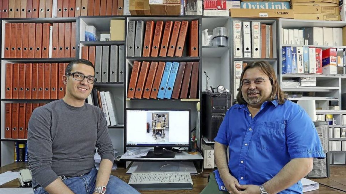 El gerente del PCM, Rafael Pablos (dcha.) y su compañero Leo, con una imagen del robot.-ICAL