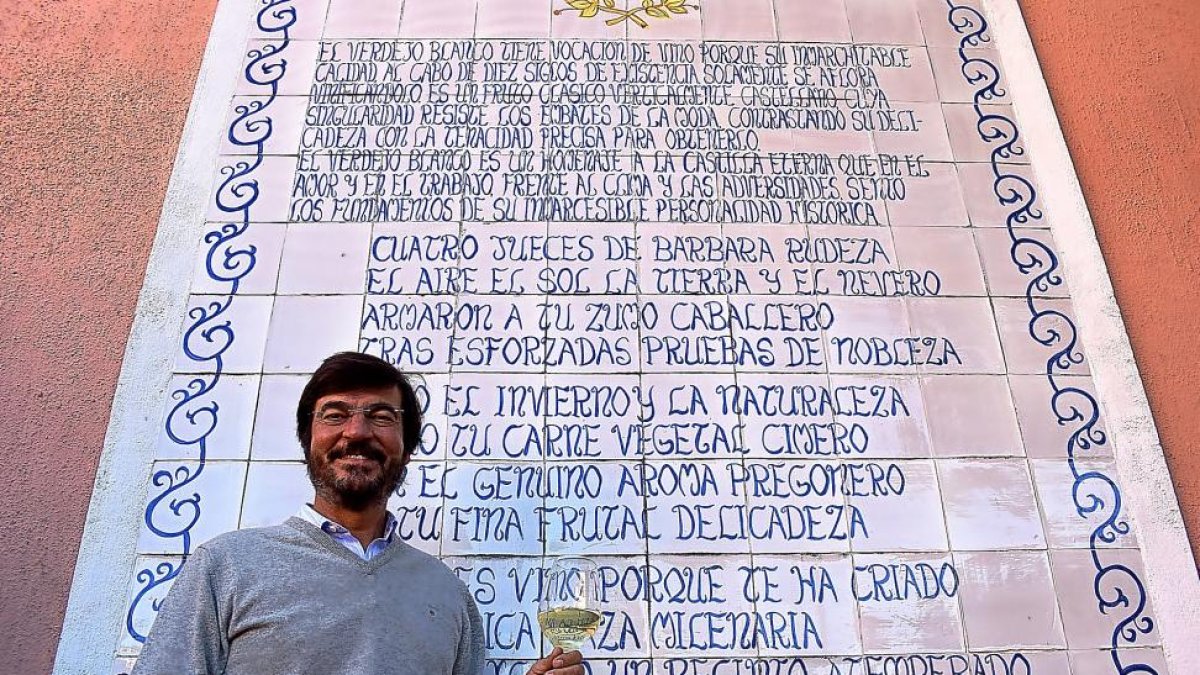 Juan de Benito, junto al soneto de su padre dedicado al vino verdejo, que luce en la pared del patio central de su bodega navarresa.-ARGICOMUNICACIÓN