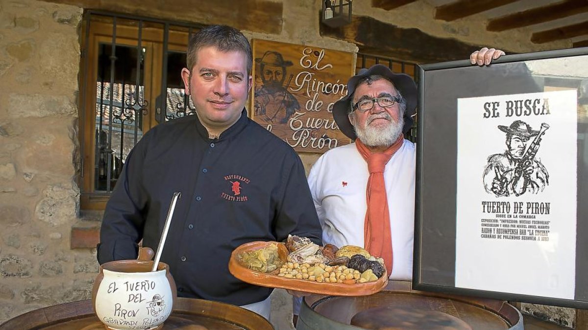 Isaac, con un grabado del bandolero, junto a su hijo Rubén, que sostiene el cocido que ha hecho célebre a su restaurante familiar de Cabañas de Polendos.-ARGI