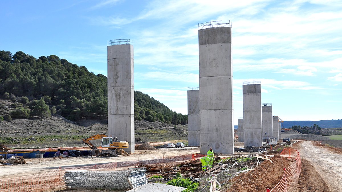 Dos operarios clasifican ferralla al pie de los soportes del viaducto, junto a Valbuena - S. G. C.