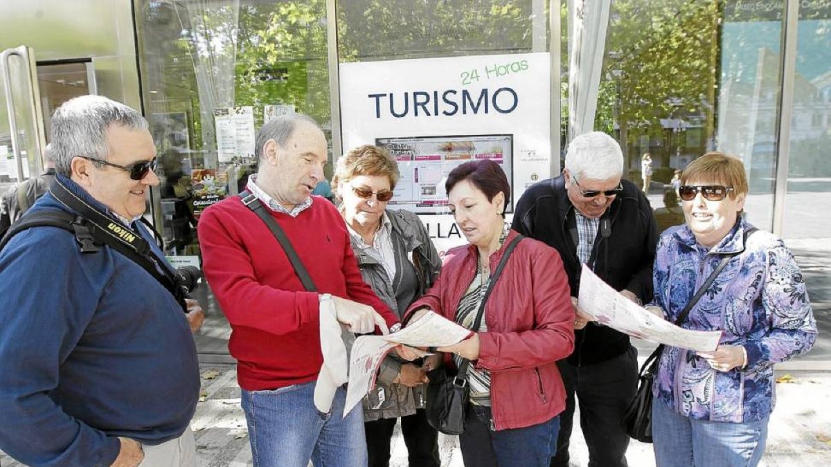 Visitantes consultan un folleto a la salida de la Oficina de Turismo de Valladolid de la Acera de Recoletos-J.M.Lostau