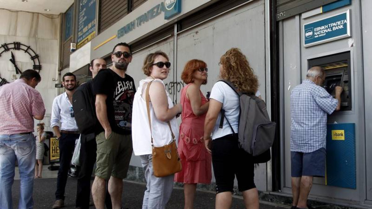 Atenienses hacen cola ayer para retirar dinero de un cajero automático en una sucursal del Banco Nacional de Grecia, en Atenas (Grecia).-Foto: EFE