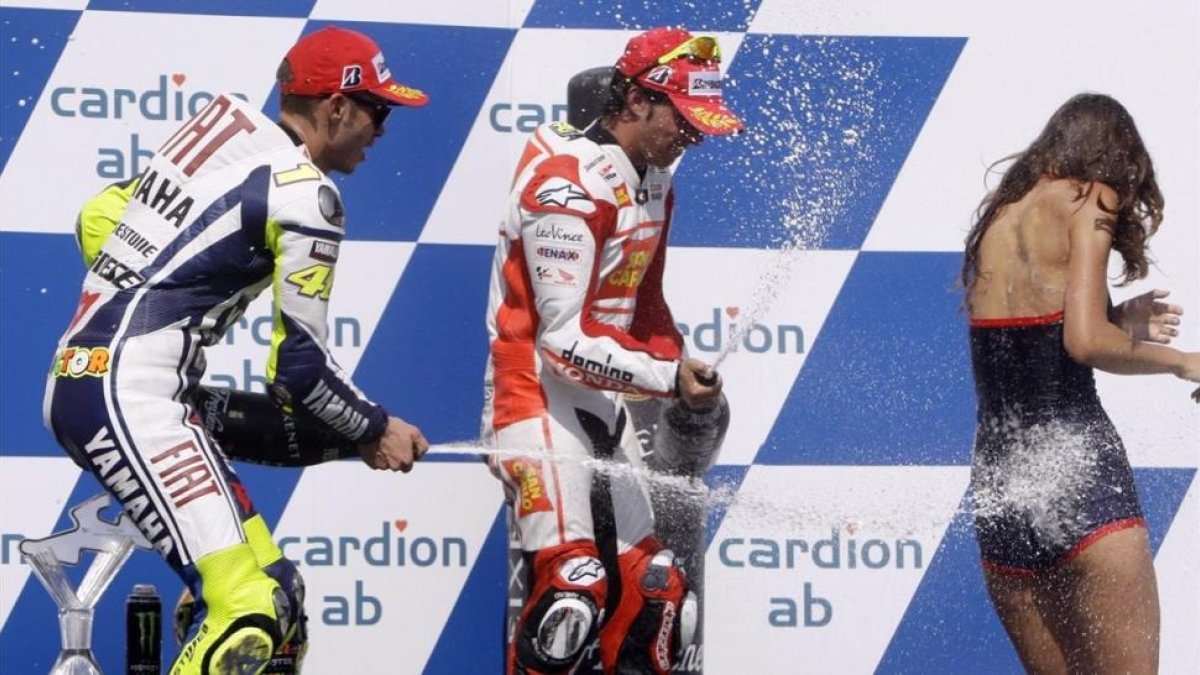 Valentino Rossi y Toni Elias rocían a una azafata con champán en el podio de Brno, en el 2009.-REUTERS / PETR JOSEK