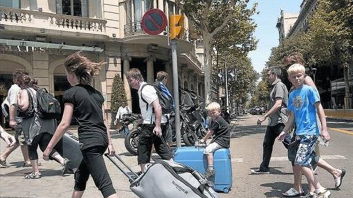 Turistas con maletas rumbo a su alojamiento recorren el paseo de Gràcia.-Foto:   JOAN CORTADELLAS