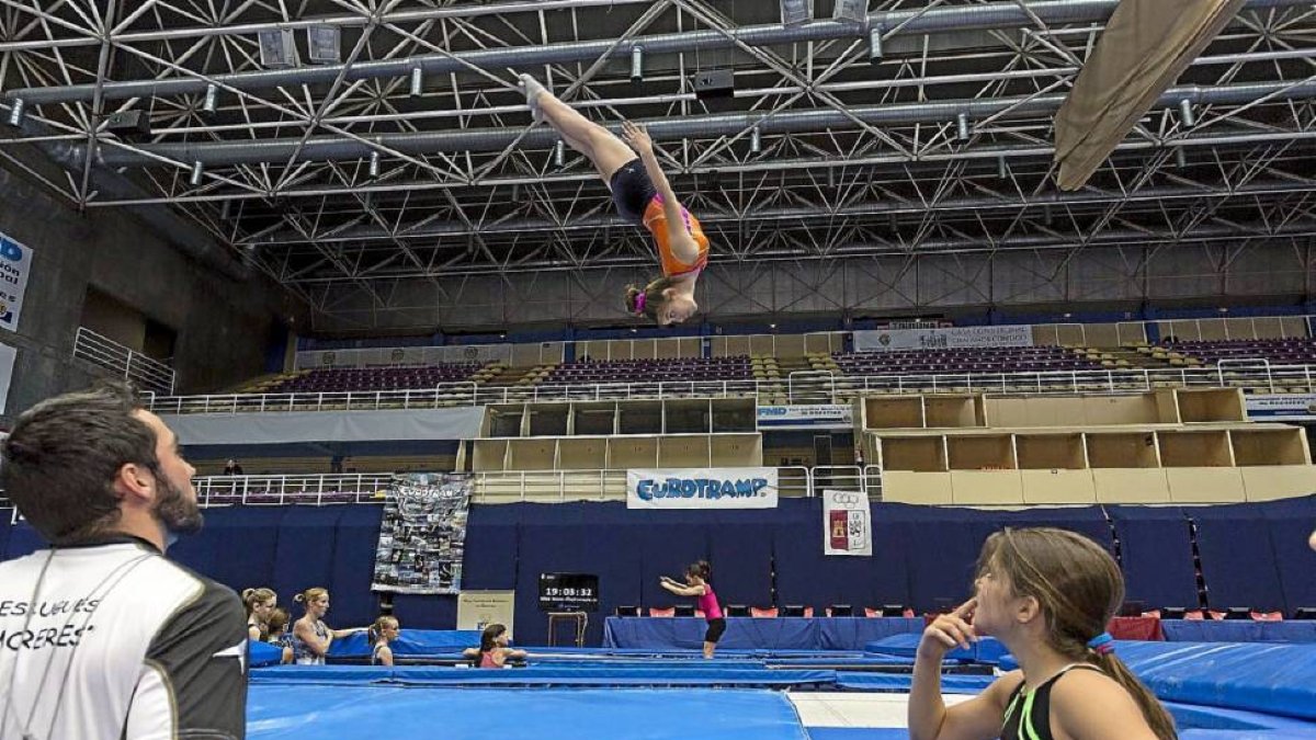 Un técnico y una gimnasta observan el salto mortal de una participante durante la jornada de entrenamientos de este jueves.-Miguel Ángel Santos