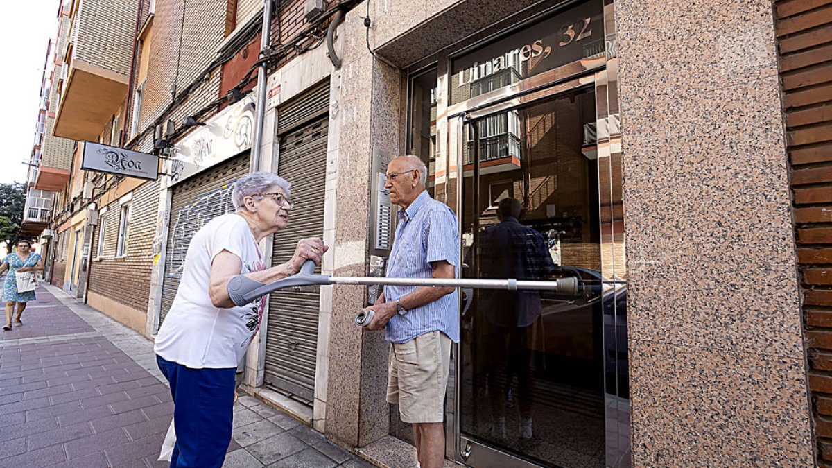 Vecinos comentan el suceso en el número 32 de la calle linares, uno de los portales donde ocurrieron los hechos. / PABLO REQUEJO / PHOTOGENIC