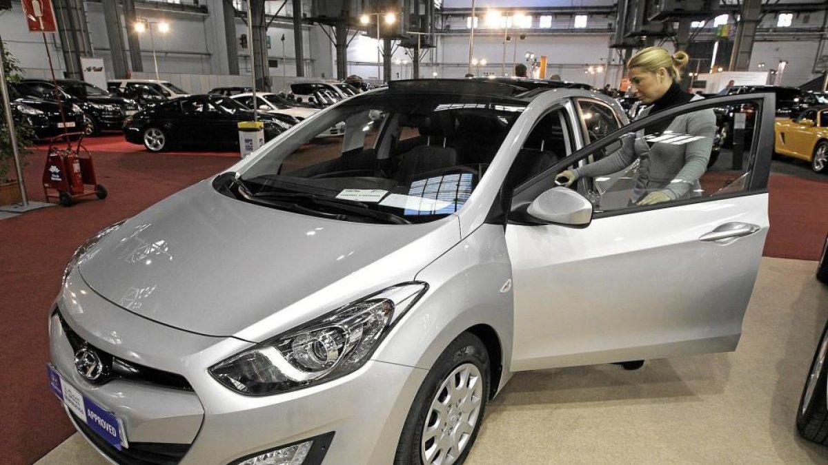 Una mujer observa un coche de ocasión en una feria del automovil.-ANTONIO MORENO