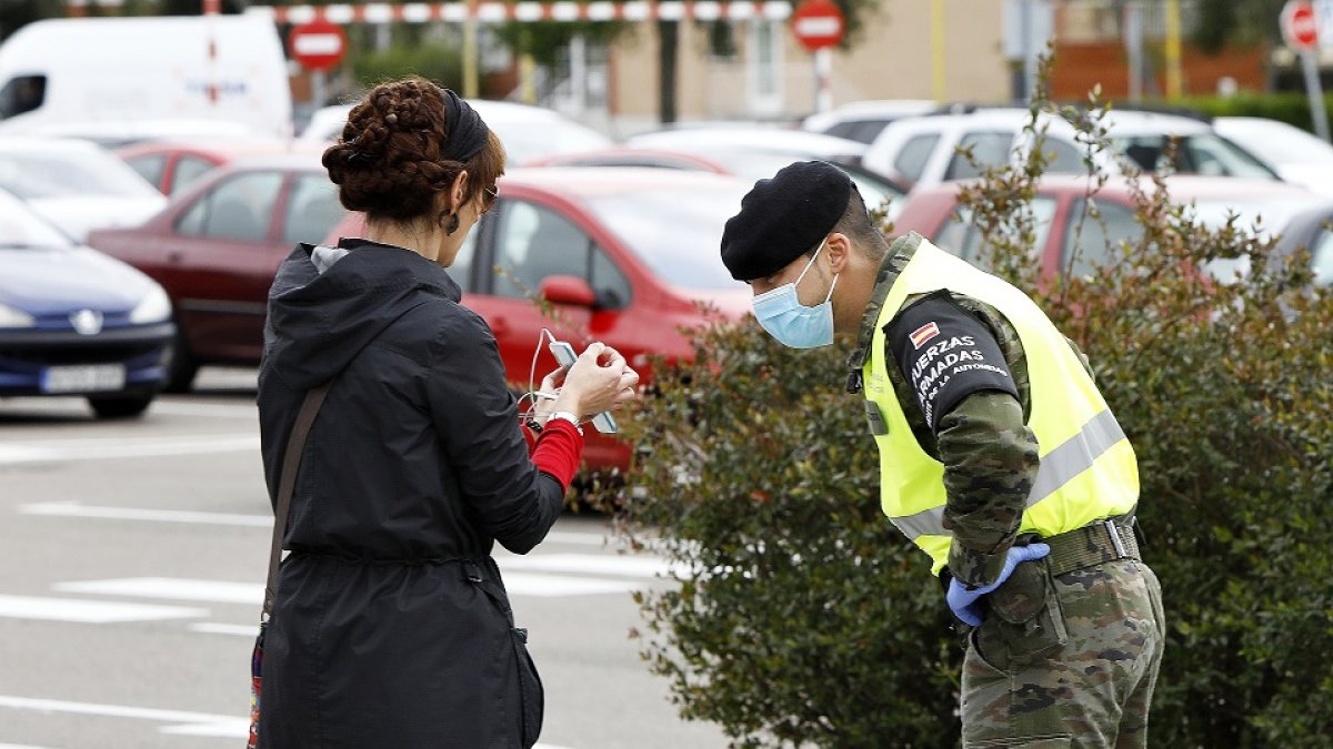 Un efectivo de las Fuerzas Armadas revisa la autorización de salida de una viandante. J.M. LOSTAU