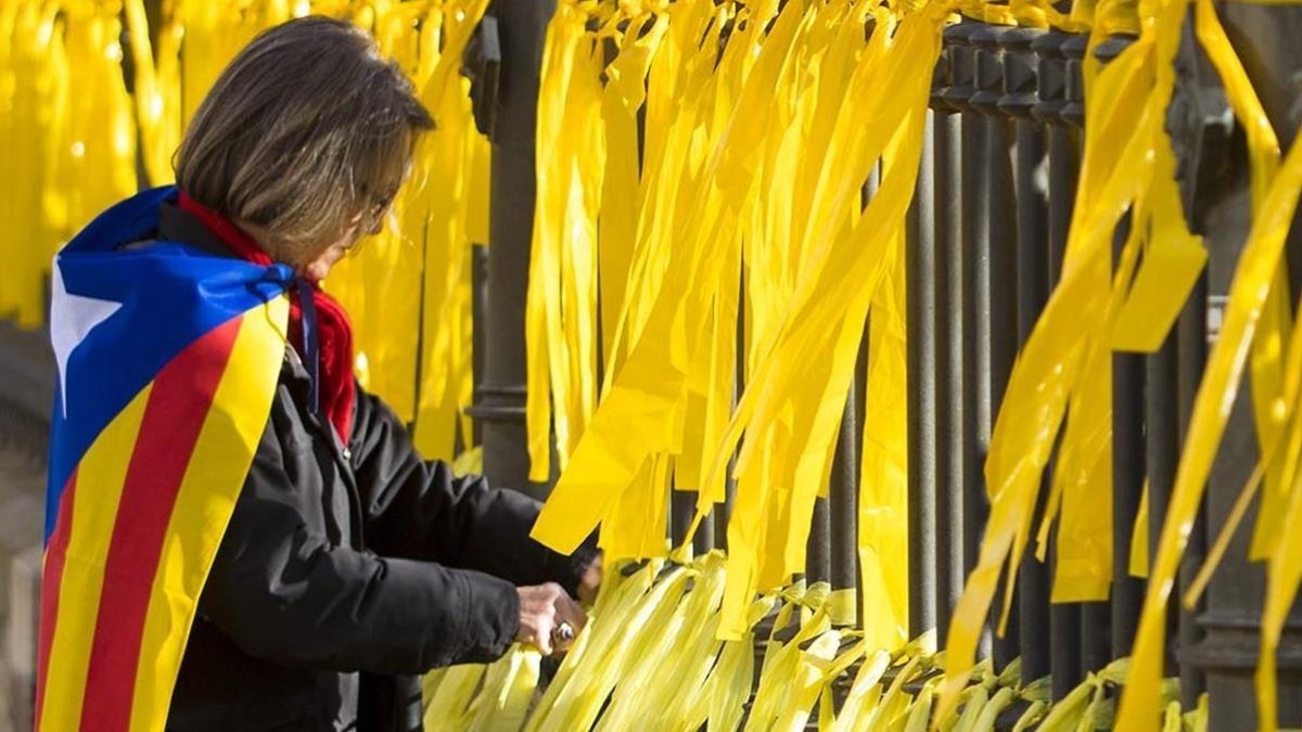 Una mujer coloca lazos amarillos en una verja-FERRAN NADEU
