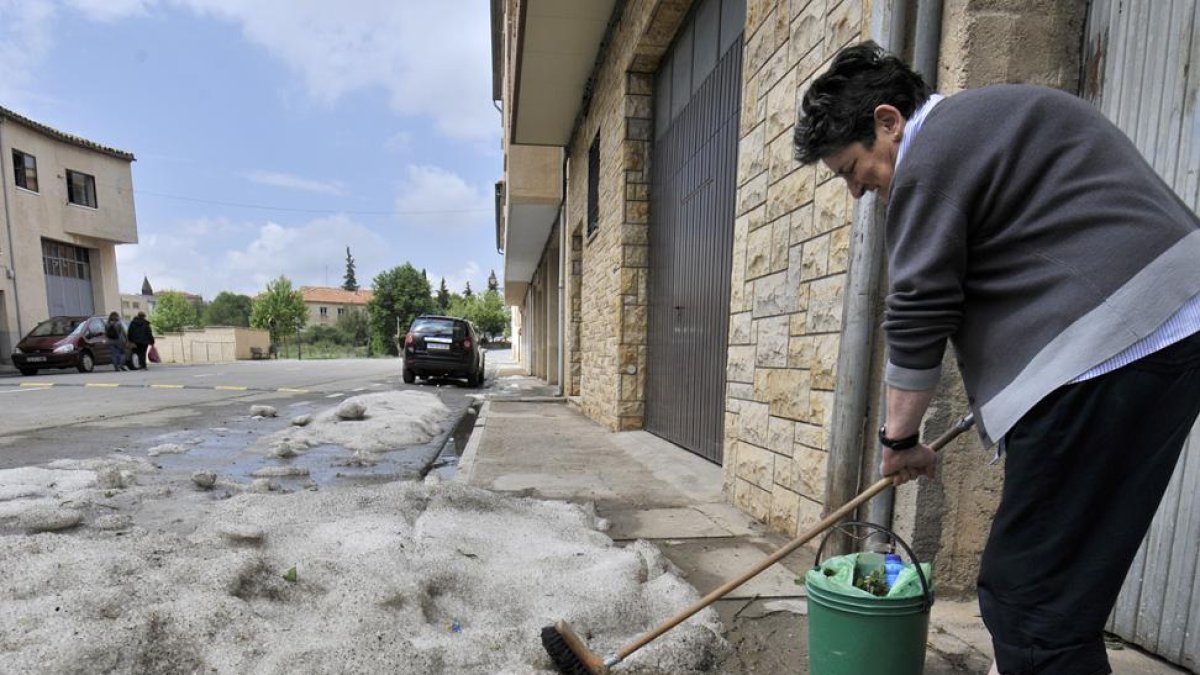 Una vecina limpia el granizo en la puerta de su vivienda.-VALENTÍN GUISANDE