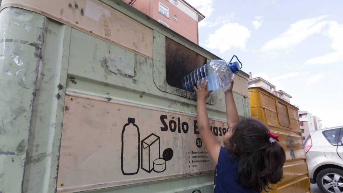Una niña reciclando un envase de plástico en un contenedor en Valladolid.-Miguel Ángel Santos