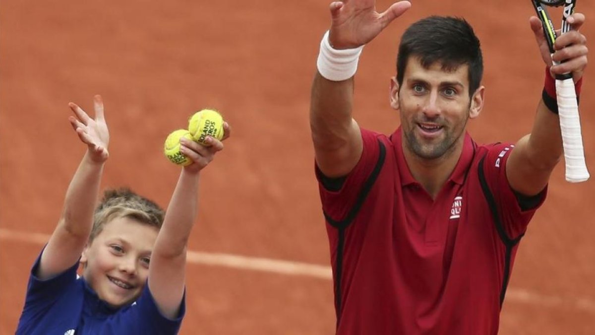 Djokovic celebra la victoria ante Berdych al lado de un entusiasta recogepelotas.-AP / DAVID VINCENT
