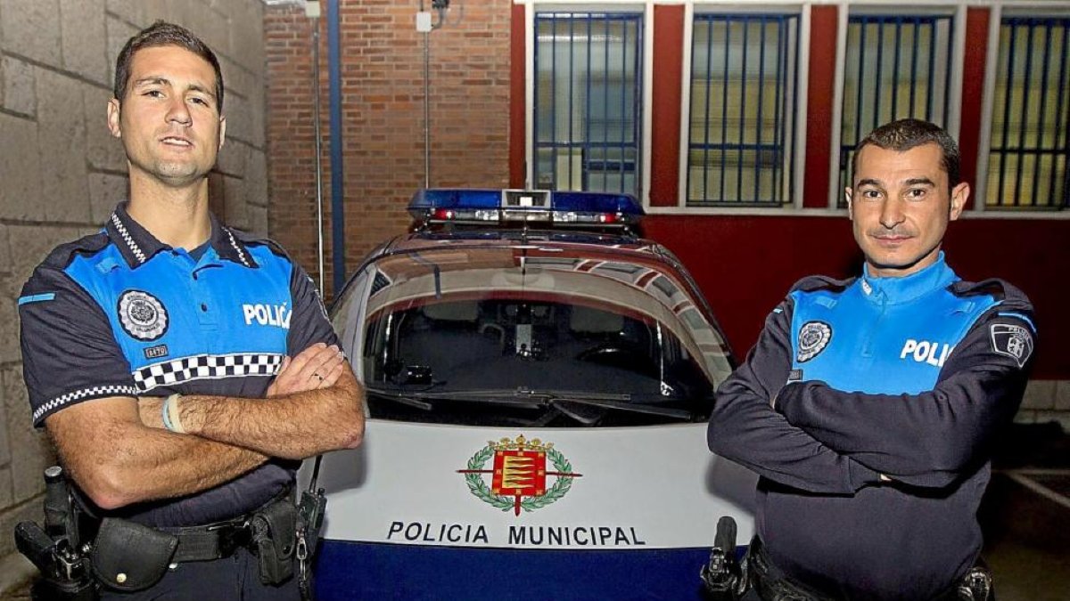Samuel Casado y Óscar Domínguez junto a uno de los coches patrulla en la Comisaría de las Delicias.-J. M. Lostau