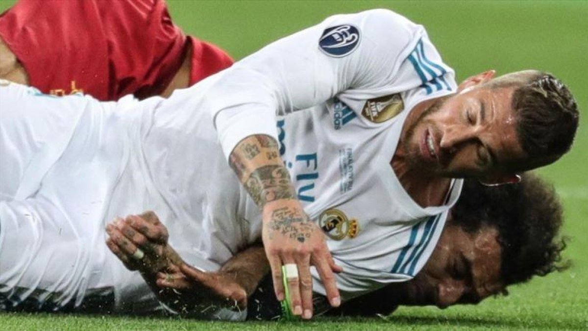 Sergio Ramos cae sobre Salah tras la disputa de un balón y le lesiona.-EFE / ARMANDO BABANI