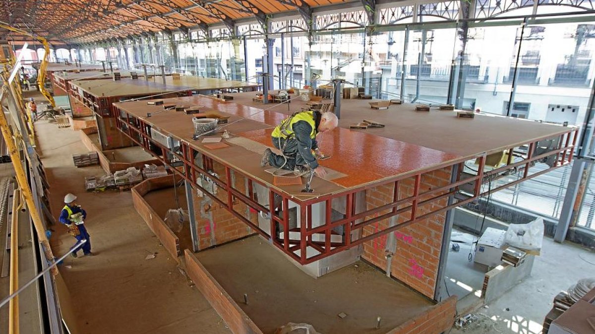 Dos trabajadores en la zona del mercado del Val que albergará los puestos.-J.M.LOSTAU