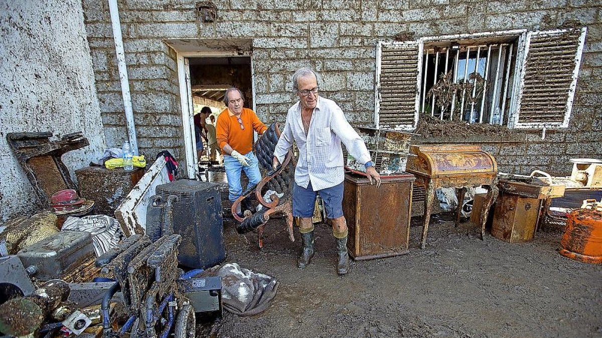 Unos habitantes de Las Navas del Marqués sacan muebles enfangados por la tormenta.-ICAL
