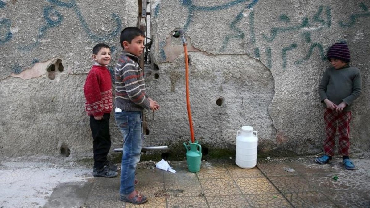 Varios niños hacen acopio de agua en la ciudad siria de Duma, cerca de Damasco.-REUTERS / BASSAM KHABIEH