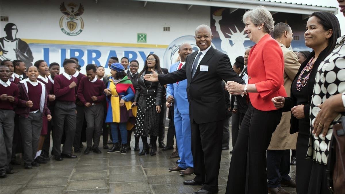 Theresa May, durante su visia a una escuela de Ciudad del Cabo, donde se ha arrancado a bailar. /-AP