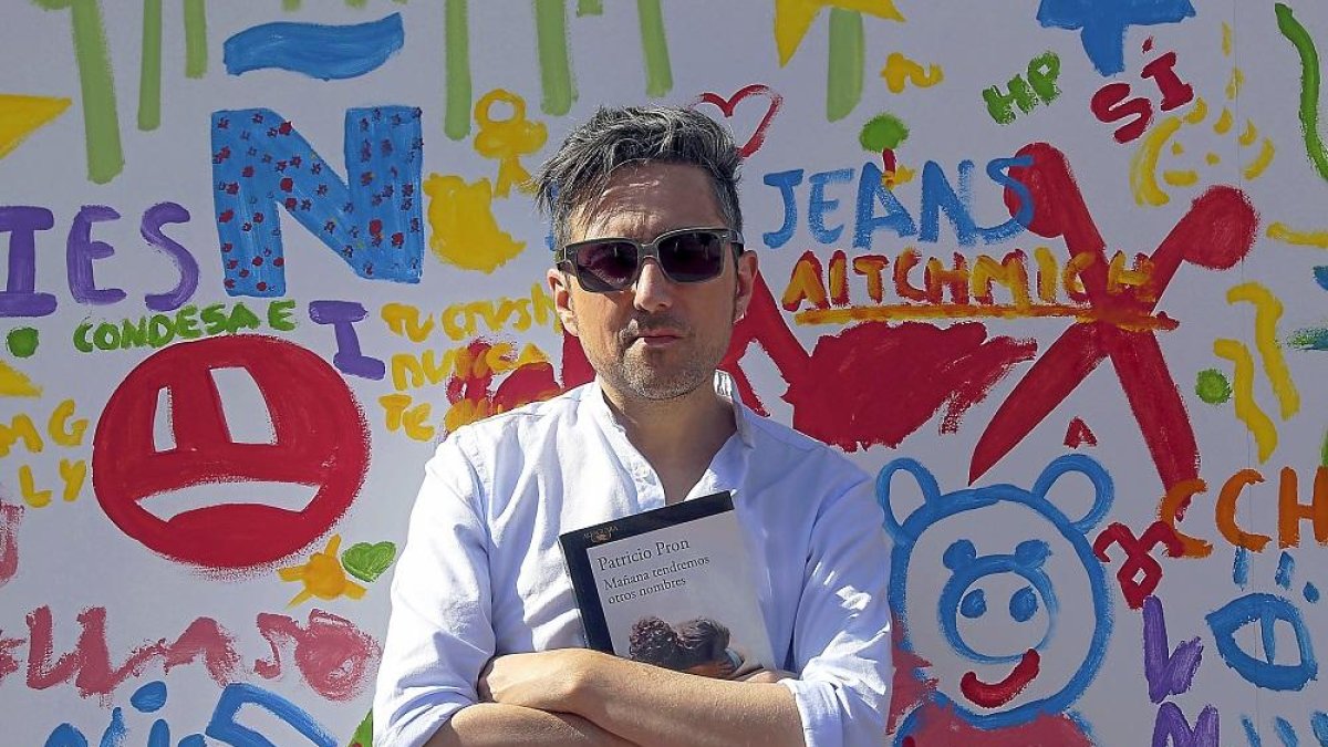 Patricio Pron posa ante una caseta de la Feria del Libro.-ICAL