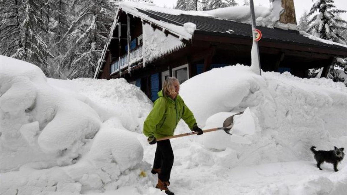 Una mujer limpia la nieve de los accesos a su casa en Val dIsere, en los Alpes franceses.-AFP / JEAN-PIERRE CLATOT