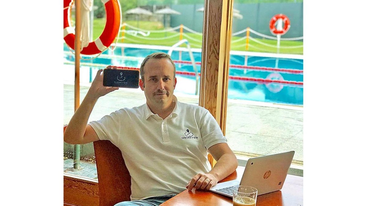 El emprendedor leonés Javier Lasarte muestra la aplicación móvil con la costa mediterránea a sus espaldas.-EL MUNDO