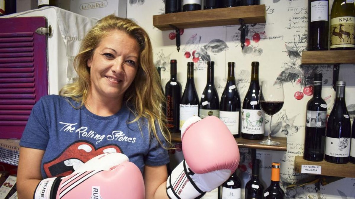 Eva Lucía Meneses, enfundada en sus guantes de kick boxing, con una copa y varios vinos de Cebreros, en su tienda de productos La Viña Bonita, situada en el centro de la capital abulense.-ARGI