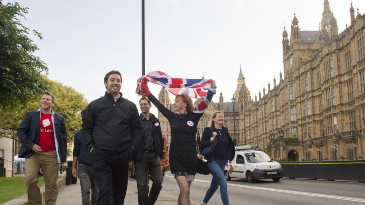 Partidarios de abandonar la UE celebran el resultado del referéndum mientras pasan frente al Parlamento, en Londres.-AP / ANTHONY DEVLIN