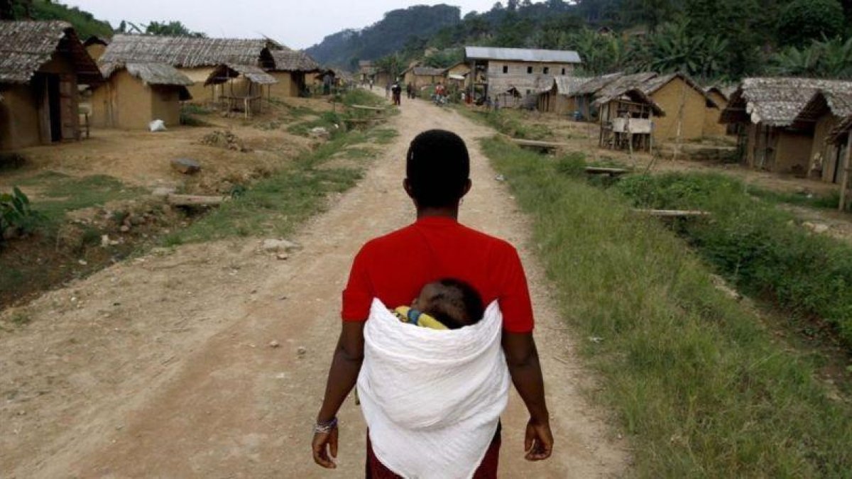 Una mujer congoleña se dirige caminano con su hijo en la espalda hacia la aldea de Luvungi.-AFP / MARC HOFFER