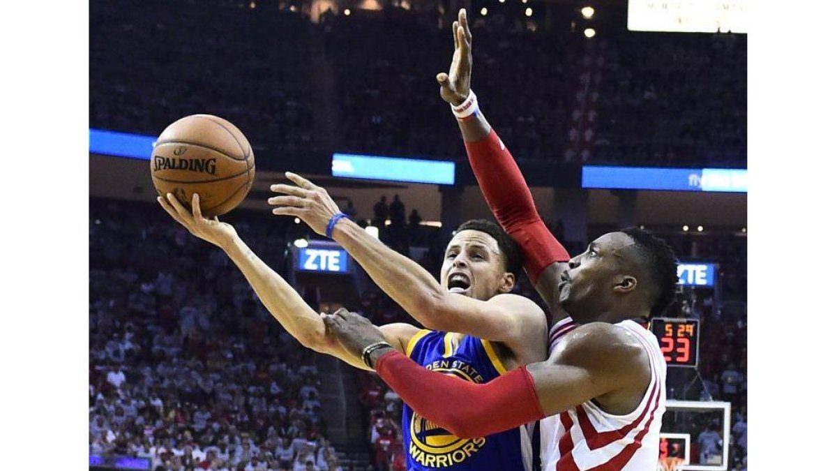 Stephen Curry entra a canasta bajo la presión de Dwight Howard.-Foto: EFE