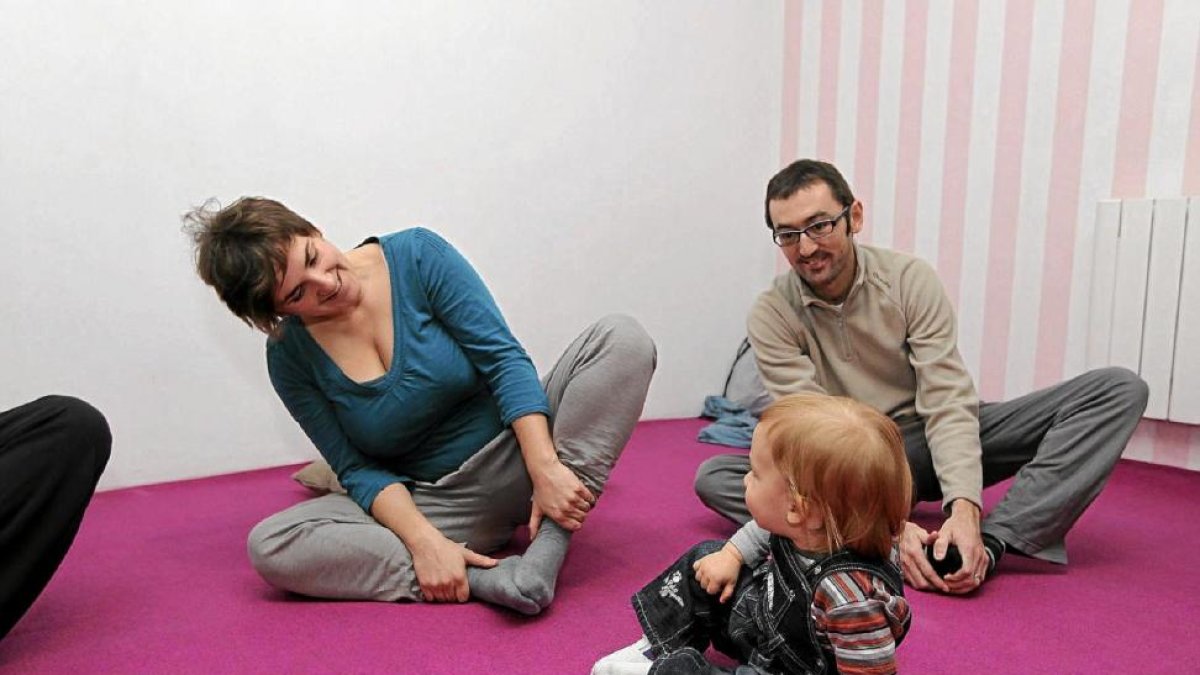 Imagen de un niño intentado imitar a sus padres mientras practican yoga-MONTSE ÁLVAREZ