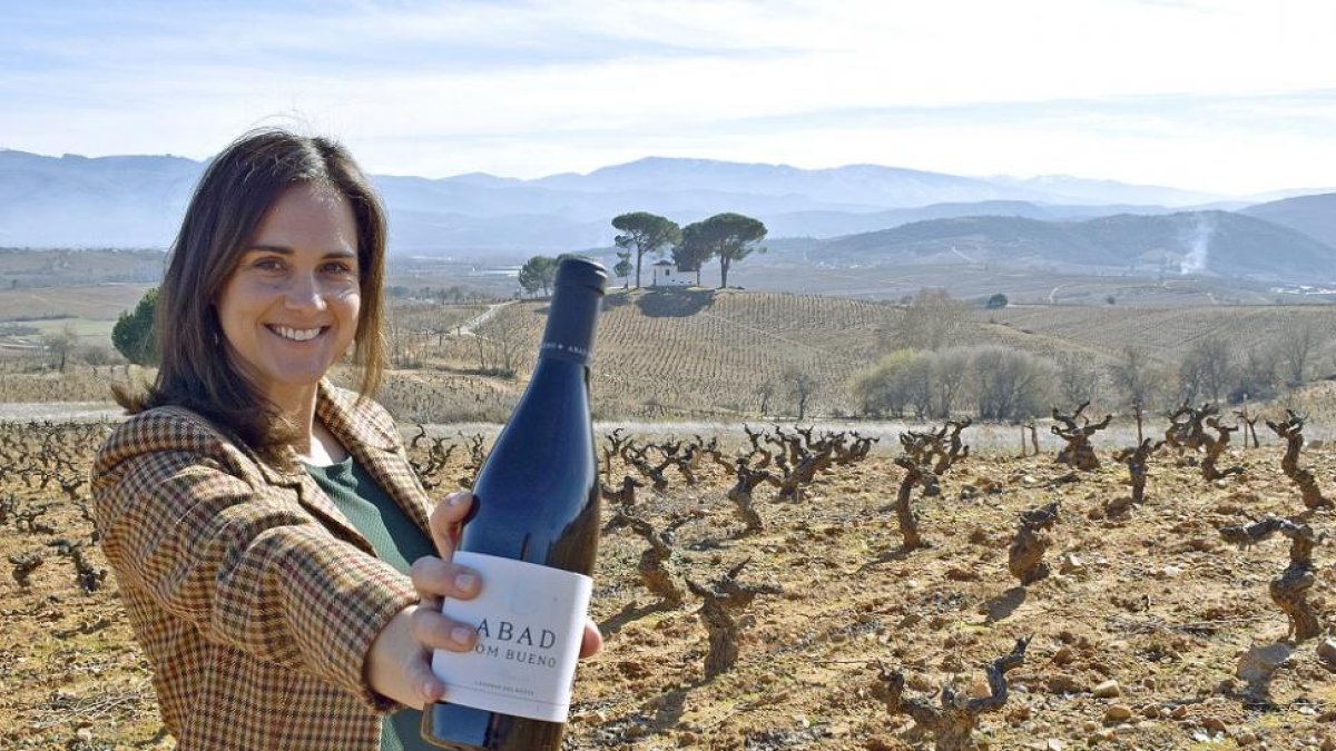 Adriana Ulibarri, con uno de los tintos de la bodega, en el lugar donde se emplazará la futura bodega, en las laderas de Valtuille de Arriba.-ARGICOMUNICACIÓN
