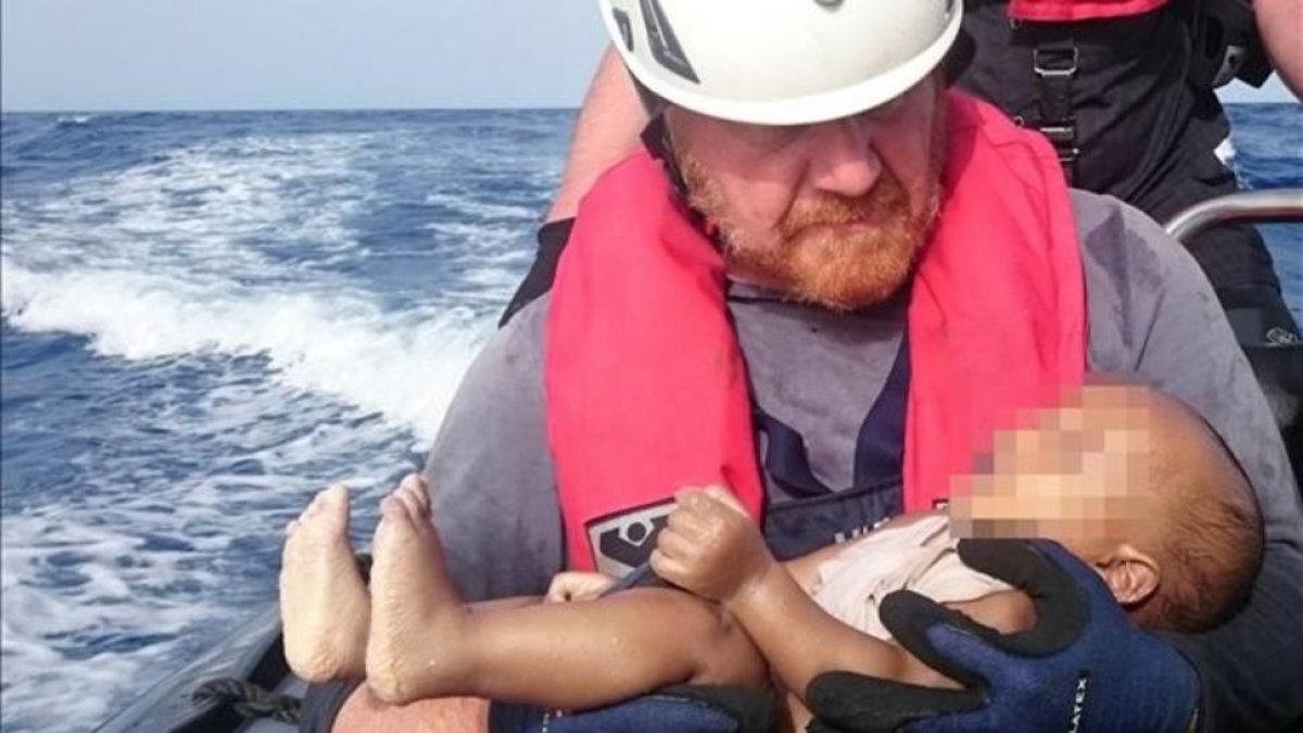 Un miembrod de la oenegé Sea Watch sostiene el cadáver de un bebé muerto recuperado de las aguas del Mediterráneo entre Libia e Italia.-CHRISTIAN BUETTNER