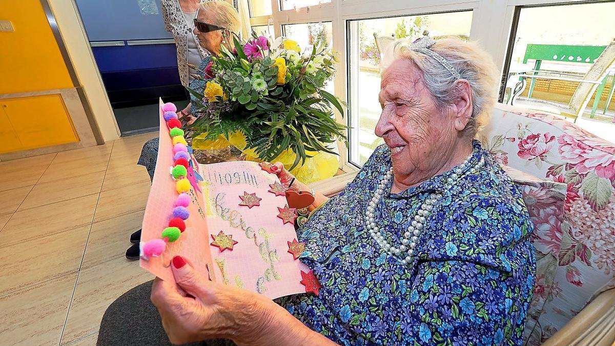 Juanita Manzanero mira ilusionada la tarjeta de felicitación regalada por los trabajadores y compañeros del centro.-PABLO REQUEJO