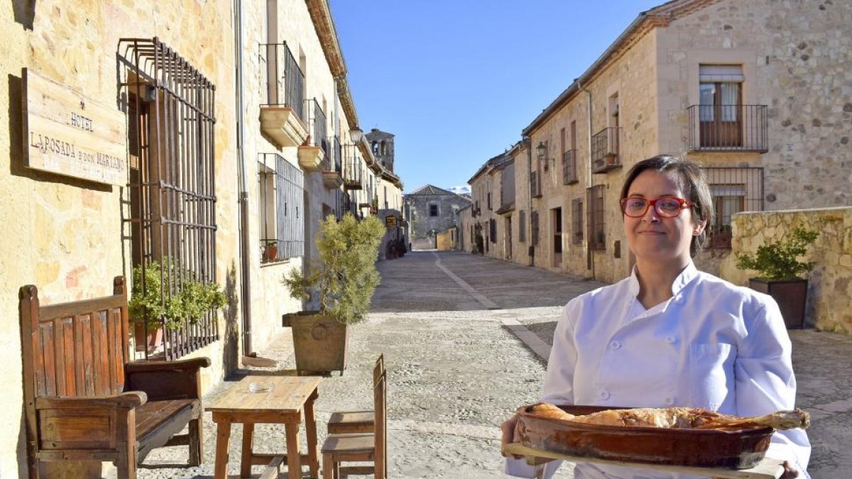 Marta Pascual, con un asado, a la entrada del restaurante, en pleno casco histórico de la villa monumental de Pedraza de la Sierra.-ARGICOMUNICACIÓN