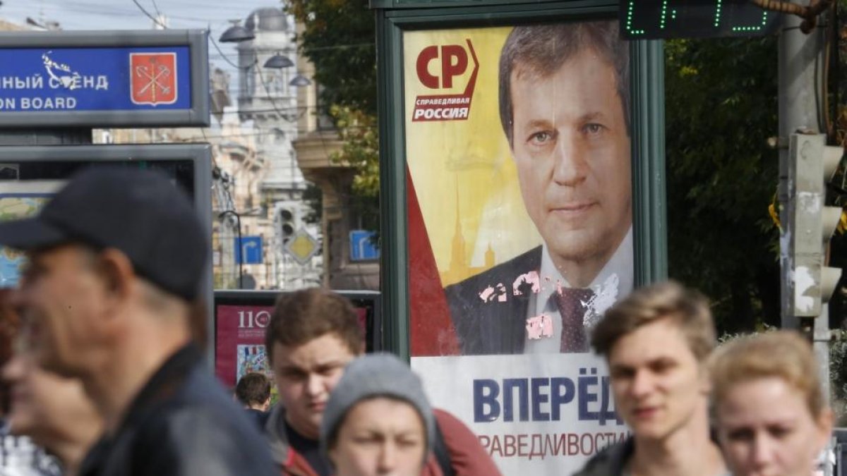 Peatones pasas por delante de un cartel electoral en San Petersburgo.-DMITRO LOVETSKY / AP