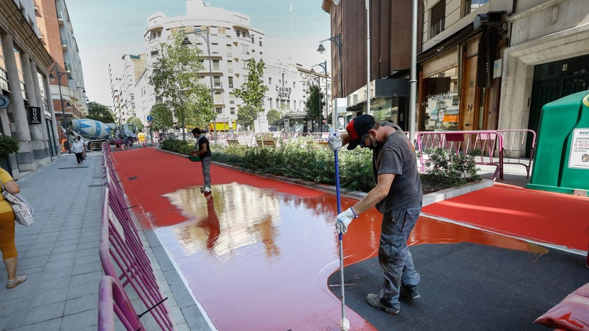 Los operarios trabajando en el asfalto rojo mate de la zona peatonal de la calle de los Doctrinos, entre María de Molina y la calle Santiago. J.M. LOSTAU
