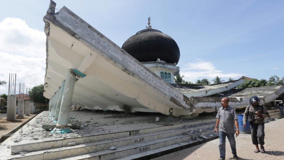 Dos vecinos pasan junto a una mezquita dañada por el terremoto, en Meuredu (Pidie Jaya).-REUTERS / ANTARA FOTO