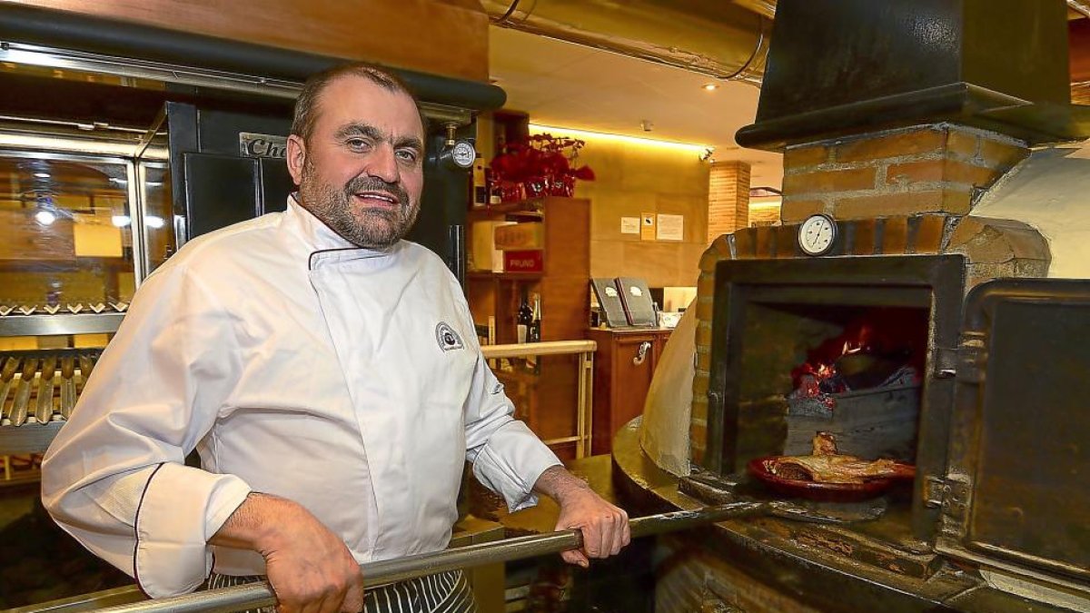 Alberto López saca un cochinillo del horno de leña del restaurante El Fogón de Salvador.-ÁLVARO MARTÍNEZ