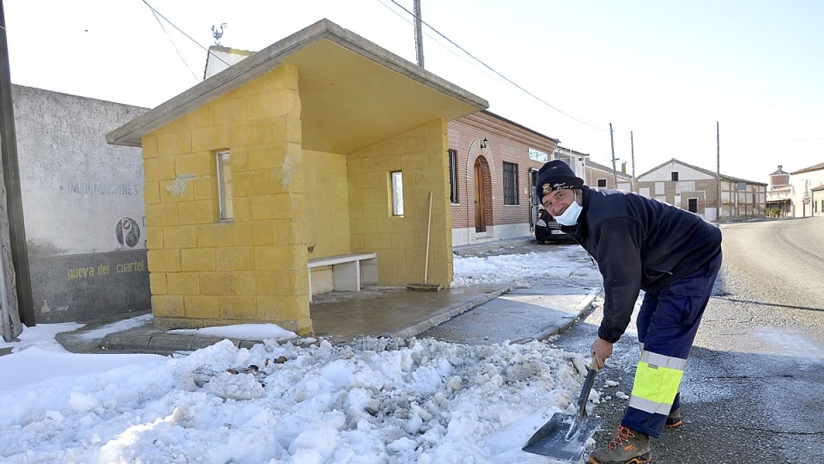 Julián, uno de los operarios municipales que acondicionan las calles y accesos a base de pala y sal, aparta la nieve de las inmediaciones de la parada del autobús, ayer en Fuente el Sol. - SGC