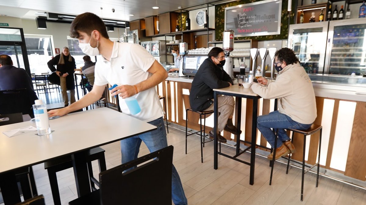 Un camarero desinfecta la mesa de un bar. / J.M. LOSTAU