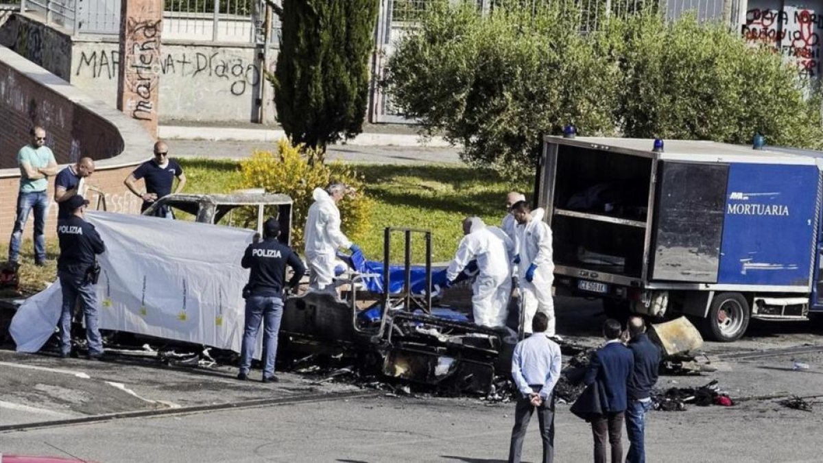 La policía forense cubre un cadáver sacado de la caravana donde murieron tres hermanas gitanas, en Roma, el 10 de mayo.-AP / MASSIMO PERCOSSI