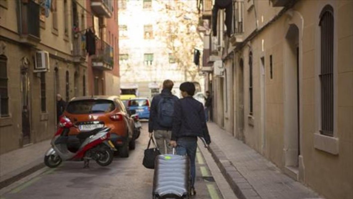 Dos turistas con su equipaje en una calle de la Barceloneta.-ALBERT BERTRAN