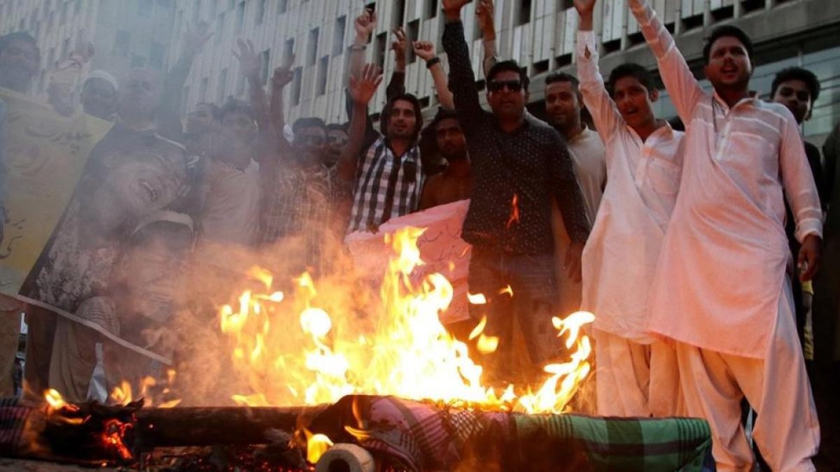 Manifestantes queman una imagen de la líder de facto de Birmania, Aung San Suu Kyi, durante una protesta contra la persecución de los rohinyas, en Karachi (Pakistán), el 17 de septiembre.-EFE