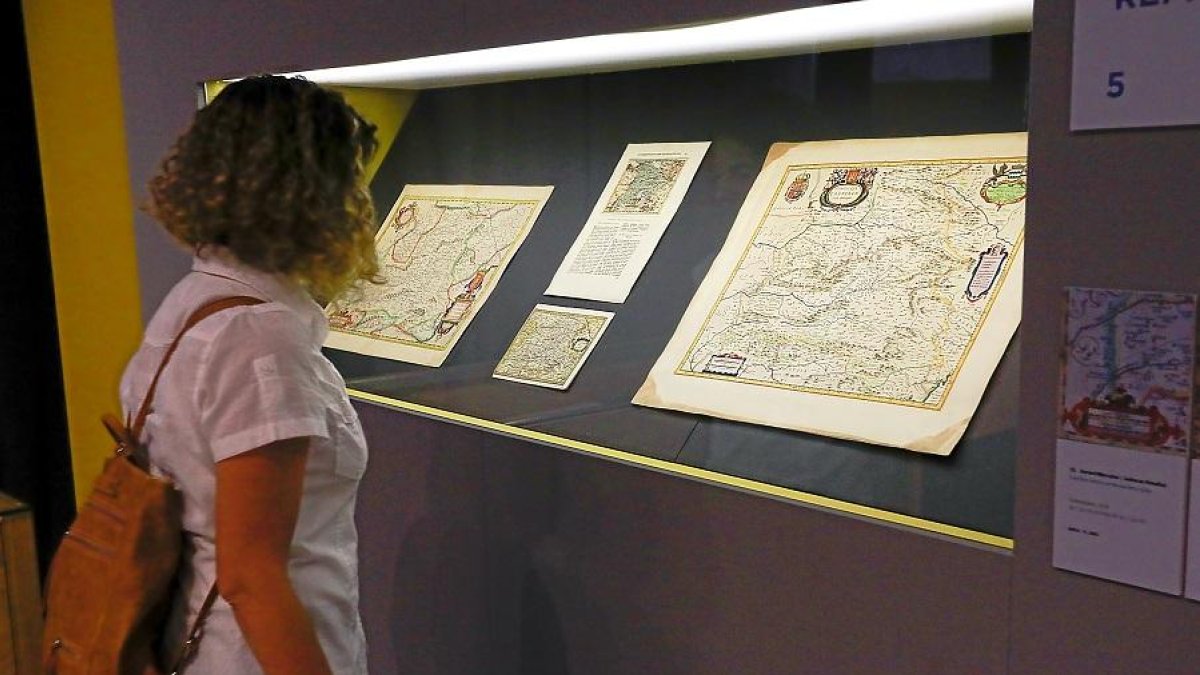 Una joven contempla algunos de los mapas expuestos en el Archivo municipal.-J. M. LOSTAU
