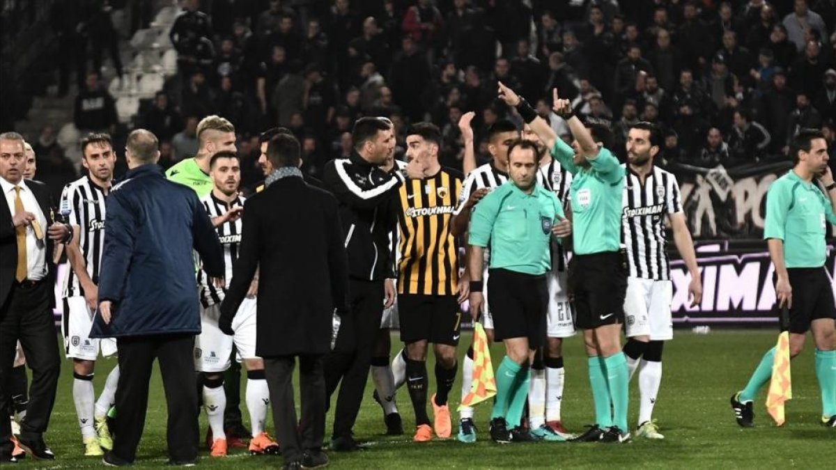 Árbitros y jugadores, durante los incidentes en el tramo final del partido en campo del PAOK.-/ AFP / SAKIS MITROLIDIS