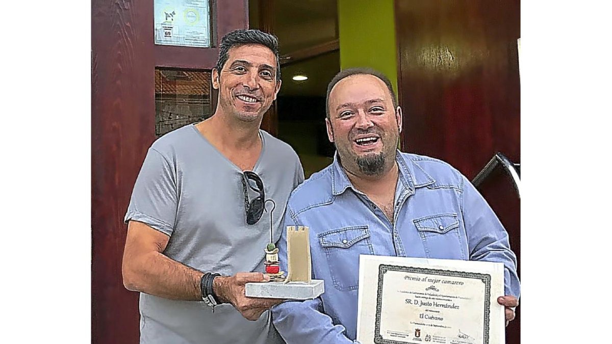 El profesional galardonado posa junto a su compañero delante el bar donde trabaja.-EL MUNDO
