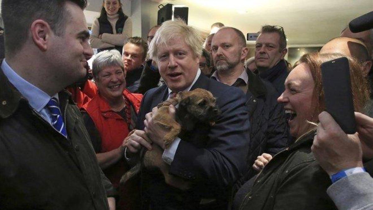 El primer ministro británico, Boris Johnson, sostiene un perro durante un encunetro con el recién elegido diputado del Partido Conservador en Sedgefield, Paul Howell, en el noreste de Inglaterra.-