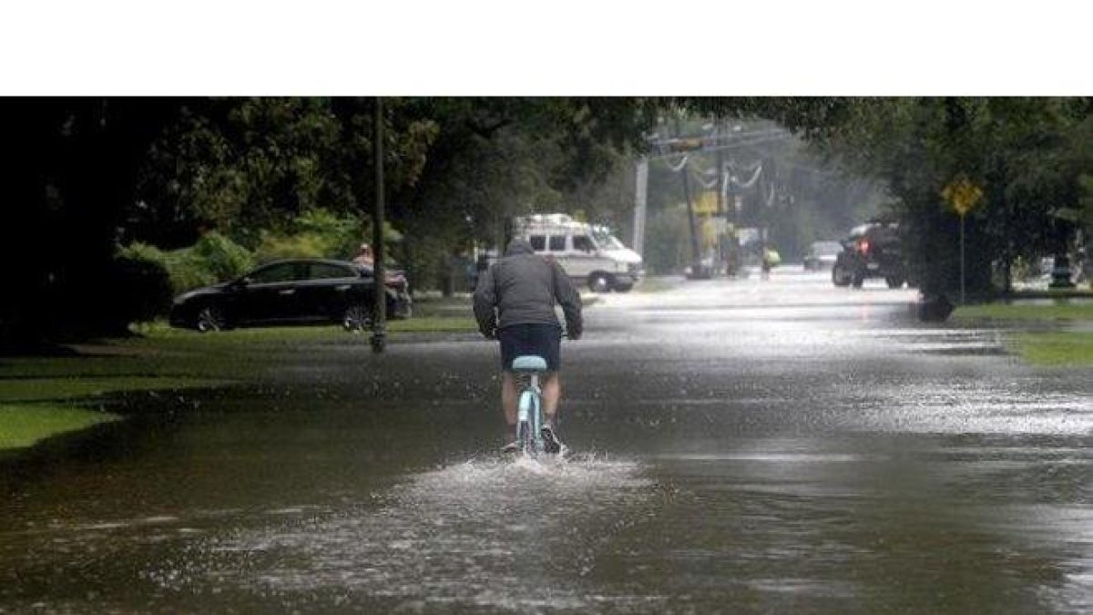 Un hombre circula con una bicicleta por una calle anegada en Beaumont (Tejas).-AP