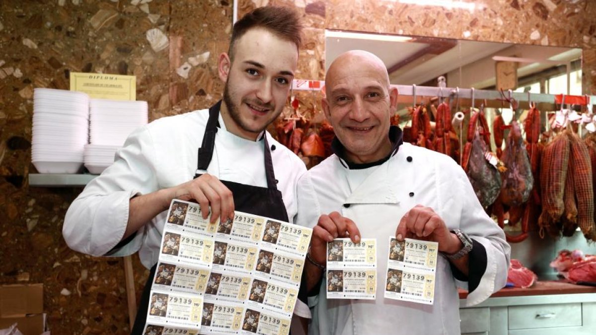 Los carniceros Juan Carlos Fernández (D) y Rubén Fernández (I), muestran los décimos premiados con 2000 euros cada uno por ser el número anterior al gordo de la Lotería de Navidad-Ical